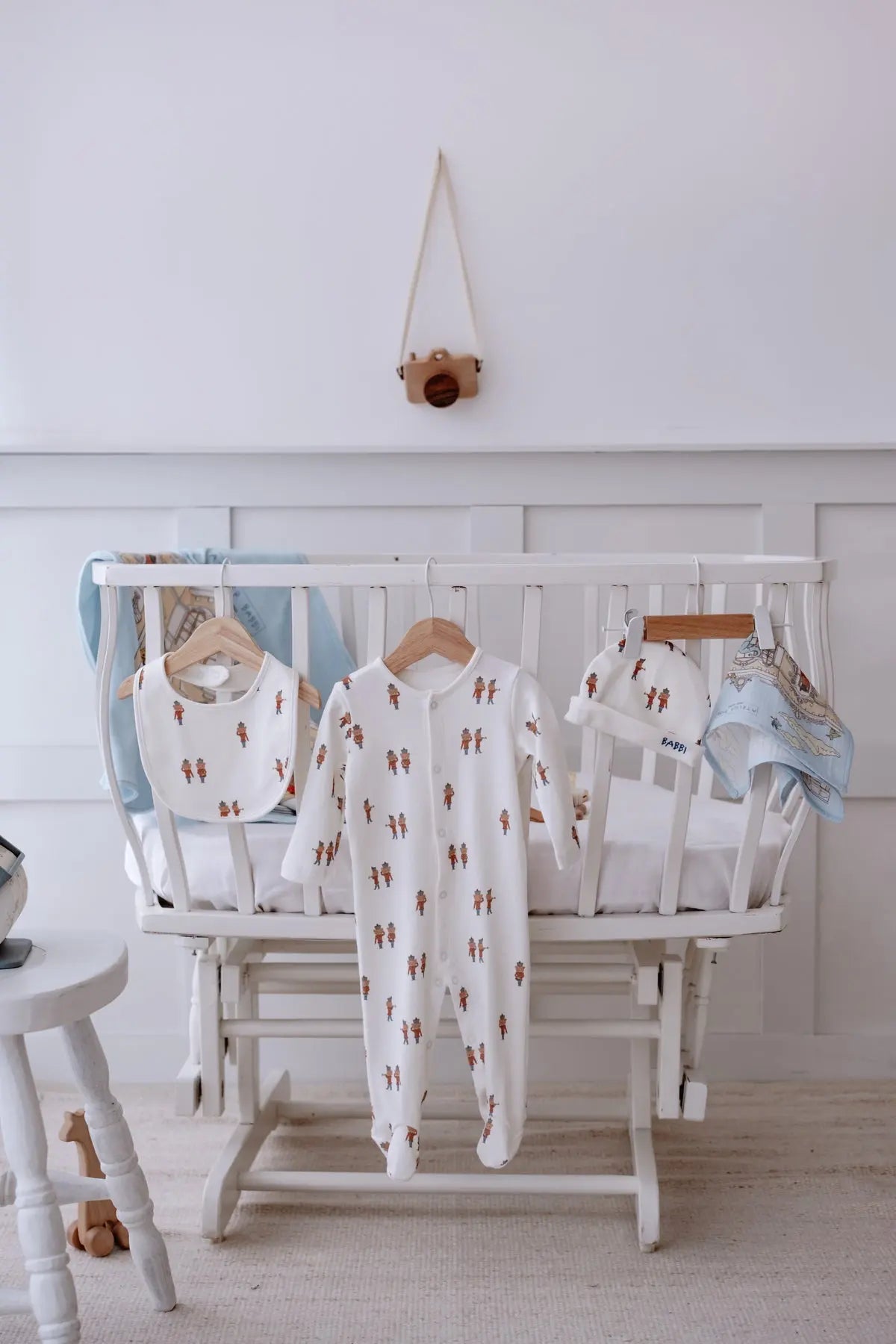 Tin Soldier 5-piece newborn set neatly displayed on a white crib, featuring a romper, bib, hat, and muslin cloth with matching whimsical soldier and palace motifs.