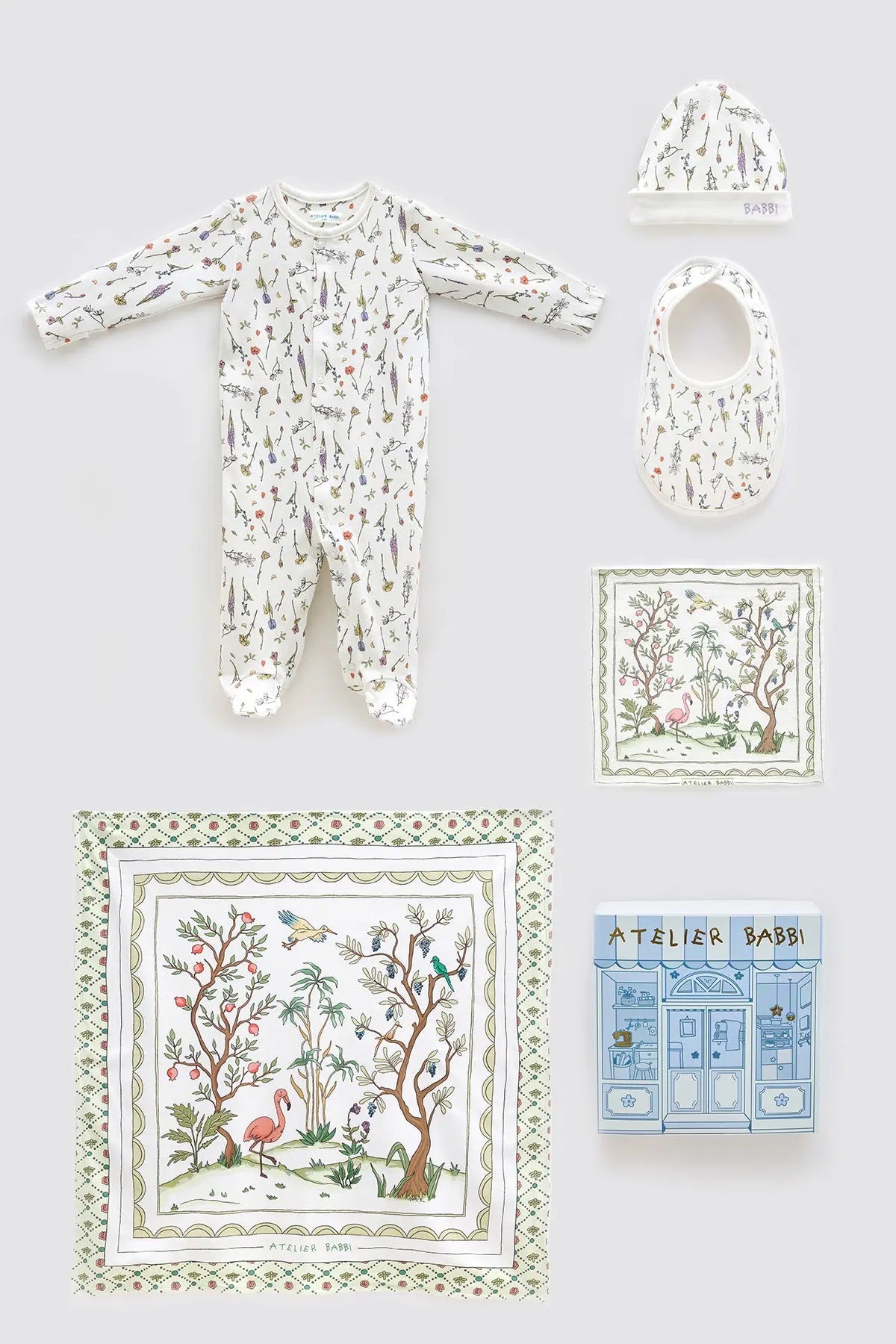 Spring-themed 5-piece newborn baby gift set by Atelier Babbi, featuring a floral print onesie, matching hat and bib, a soft muslin swaddle with bird and blossom illustrations, a mini cloth, and a boutique-style blue gift box — crafted in 100% organic cotton.