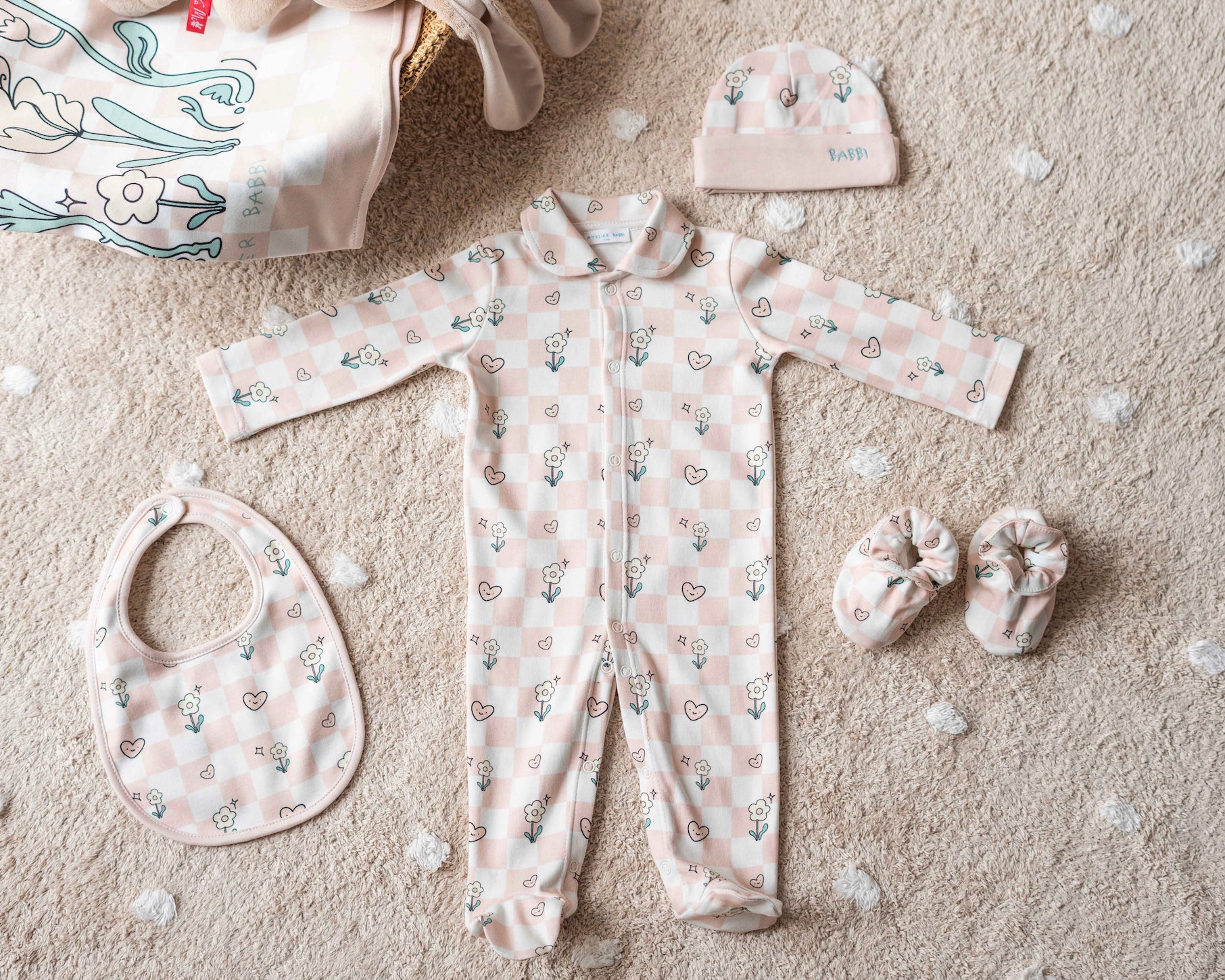 Complete 4-piece checkered baby gift set displayed in a reusable Atelier Babbi cotton pouch