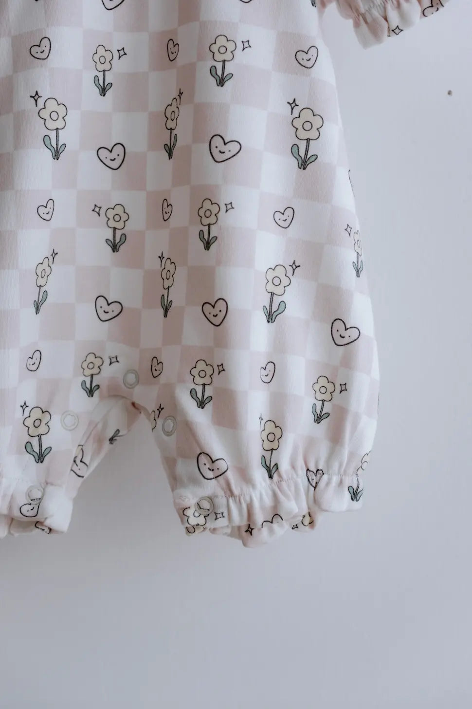 Close-up of buttons and fabric texture on checkered baby romper