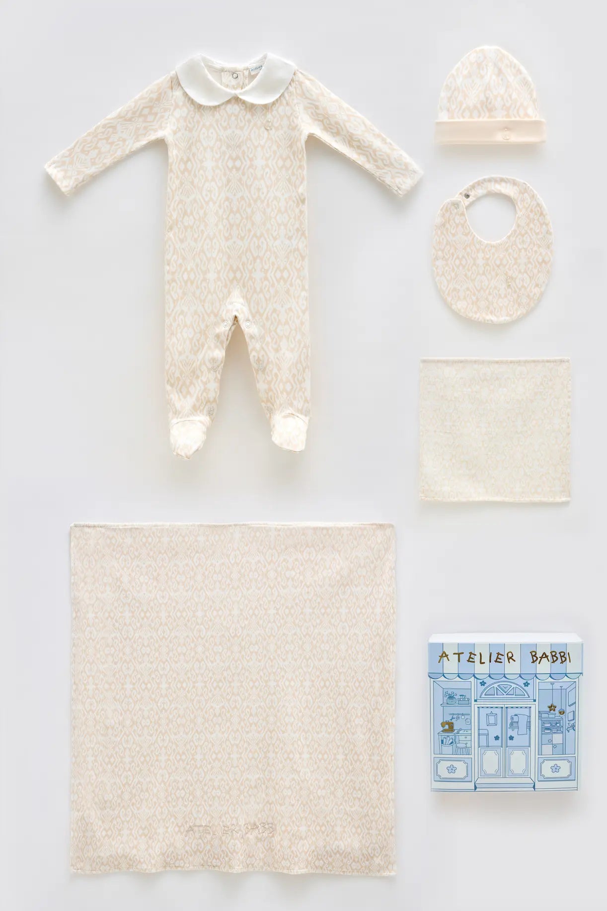 Baby clothing and accessories including a onesie, hat, bib, blanket, and book on a light gray background.