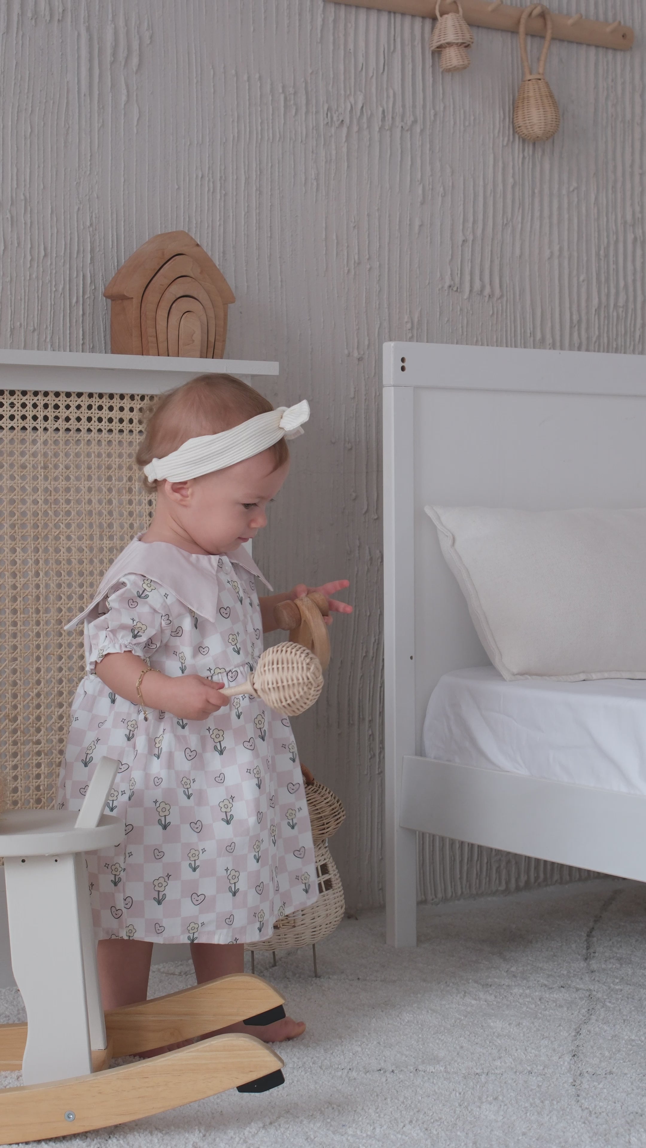Close-up video of a baby wearing a checkered dress, showing the soft fabric texture and playful movement of the outfit.
