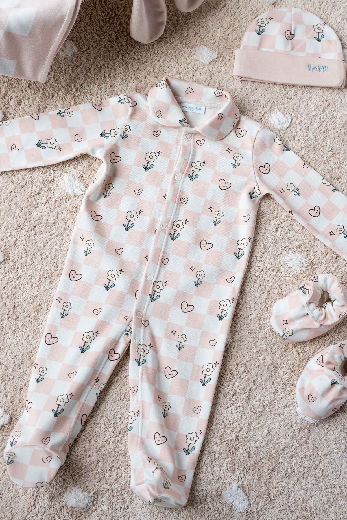 Neutral checkered baby footed onesie on beige background