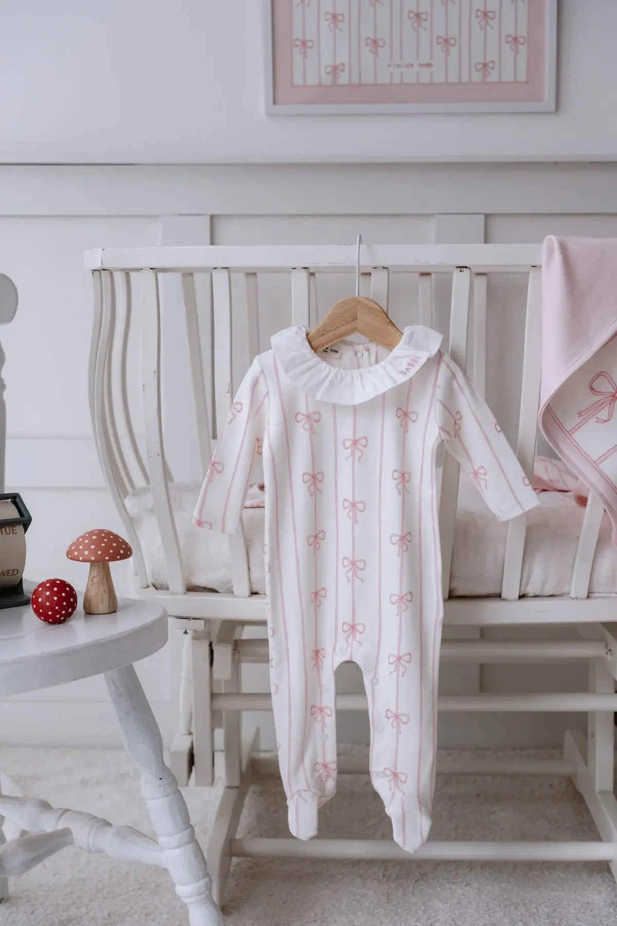Newborn girl in pink cotton footed onesie with ribbon detail