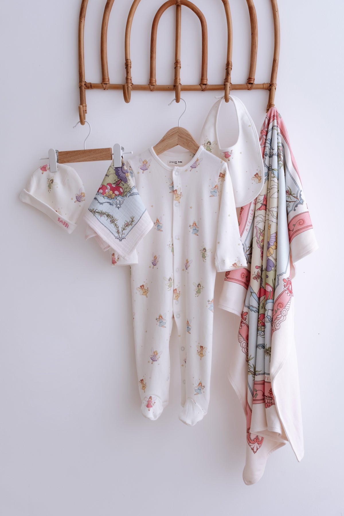 Soft organic cotton newborn gift set in Fairy Tale theme – includes romper, hat, bib, swaddle, and pouch in dreamy pastel tones.